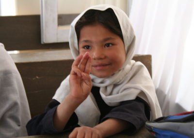 Ein Mädchen mit weißem Kopftuch macht ein Zeichen in Gebärdensprache