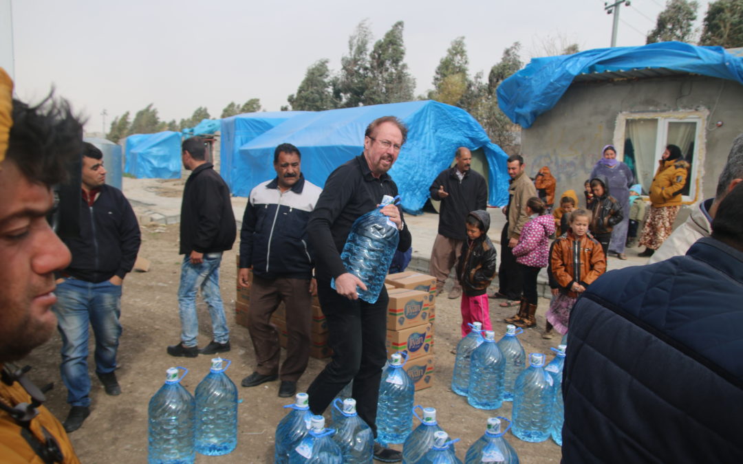 Vereinzelte Menschen stehen um ein paar Kartons und Wasserkanistern. Udo Stolte trägt einen Wasserbehälter.